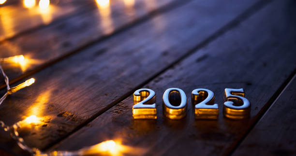 istock Metallic 2025 numbers resting on a dark wooden surface surrounded by soft glowing string lights. 2171334137