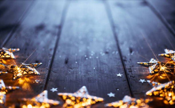 istock Glowing star-shaped lights arranged in a circle on wooden table with scattered glitter and star confetti. 2171334170