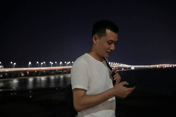 A man walking at night uses his mobile phone while walking