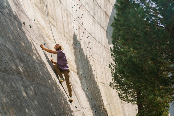 Man climbing on wall of damm used as a bouldering wall