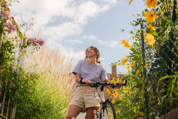Woman with bicycle among flowers on backyard