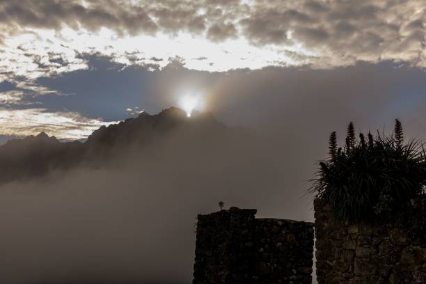 Sunrise over misty mountains with ancient stone ruins in the foreground, creating a dramatic and serene landscape.