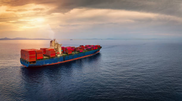 istock A large, loaded container cargo ship sailing over calm sea into the sunset 2171341318