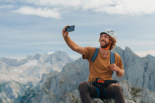 Man climbing via ferrata above Gosausee in Austria  and enjoying beautiful landscape making selfie