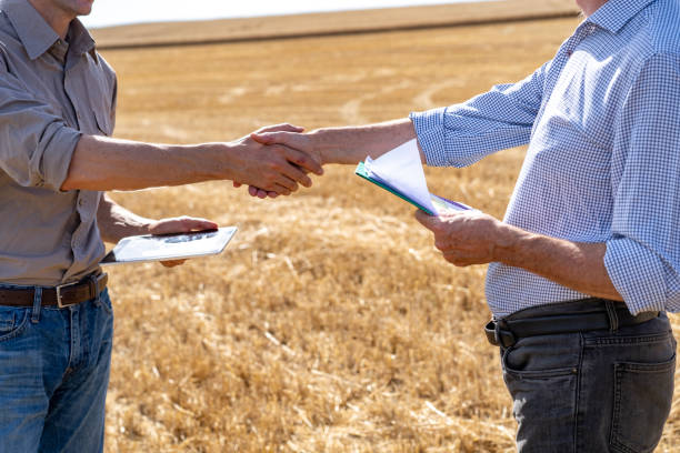 istock Two unidentified men shaking hands while standing in open agricultural field 2171342756
