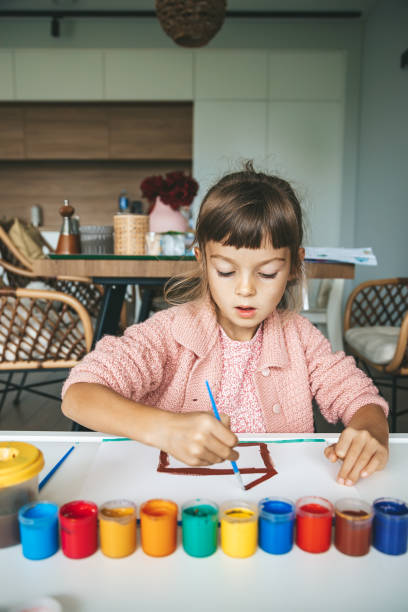 istock A young girl engaged in painting at a table, using different colors 2171345004