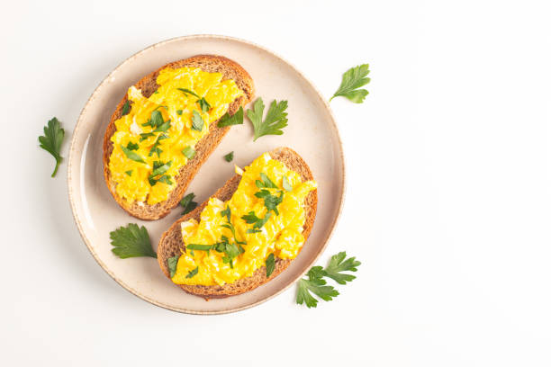 istock Scrambled eggs with green herbs on wheat-rye crispy toast. 2171351026
