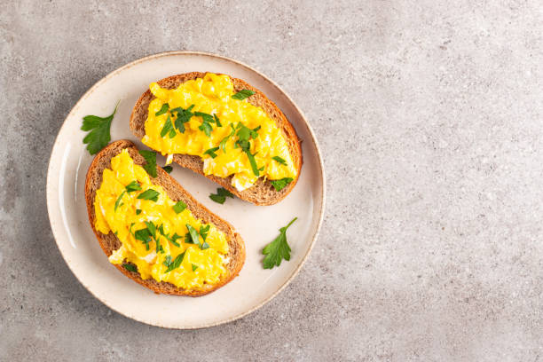 istock Scrambled eggs with green herbs on wheat-rye crispy toast. 2171351121