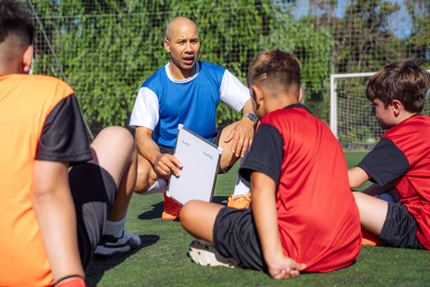 istock Soccer Coach Discussing Strategy with Young Team on Field 2171351219