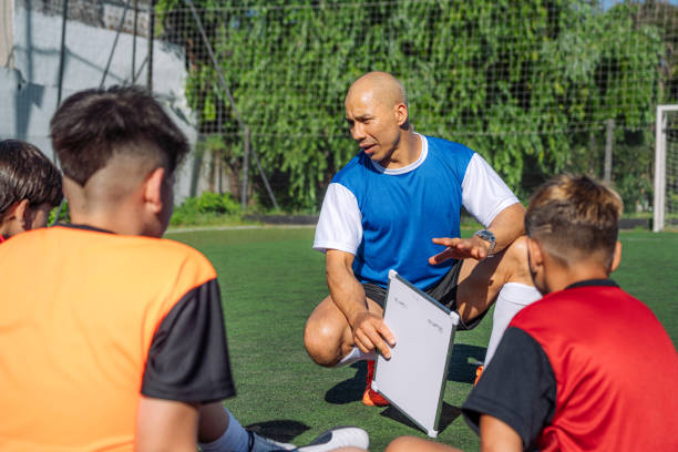 istock Soccer Coach Discussing Strategy with Young Team on Field 2171351302