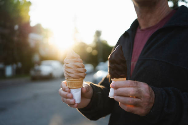 Classic waffle cone of ice-cream in a hand of an elderly person against blurred background