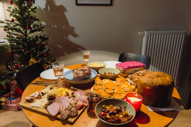 Set of celebration meals and appetisers on wooden table near the decorated Christmas tree at night during Christmas holiday celebration