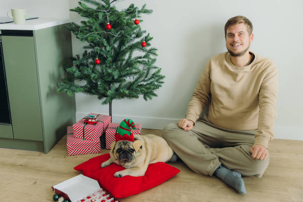 istock Cheerful Man Decorating Xmas Tree With His Cute Dog 2171354952