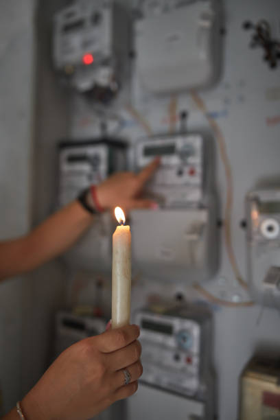 istock Checking the electricity power meter with a candle in cold winter days while there is power outage. 2171358179