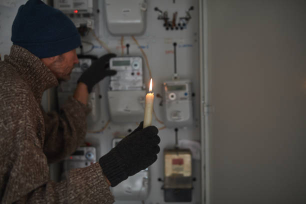 istock Checking the electricity power meter with a candle in cold winter days while there is power outage. 2171358195