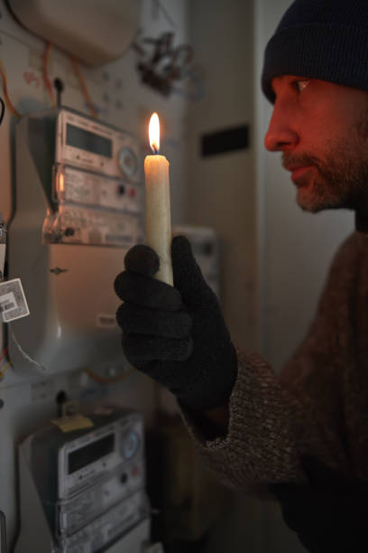 istock Checking the electricity power meter with a candle in cold winter days while there is power outage. 2171358209