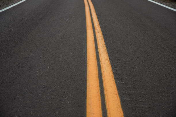 Looking down at double yellow lines on paved road.