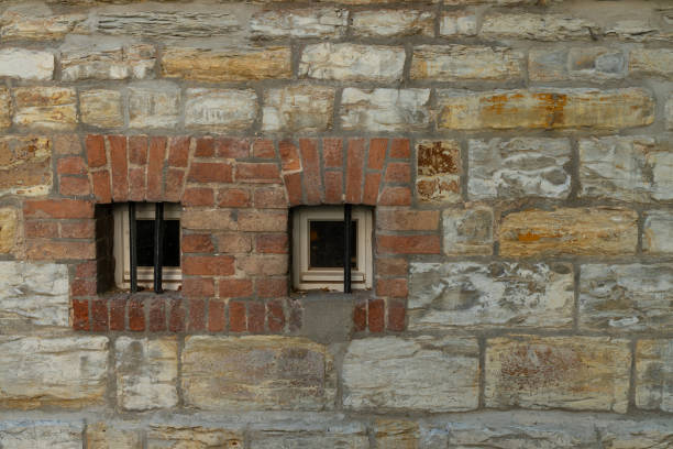 istock Historic stone wall with two barred windows in an old building 2171359905