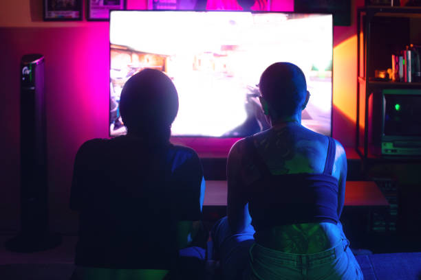 istock Two woman having fun playing video games sitting on the sofa rear view 2171361640