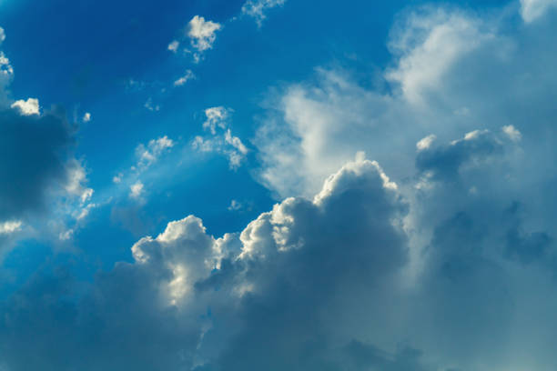 A blank for a background with a bright sky, with clouds of different sizes, illuminated by the sun's rays passing through them, and blue. Designed for designers, mockups, filler design element