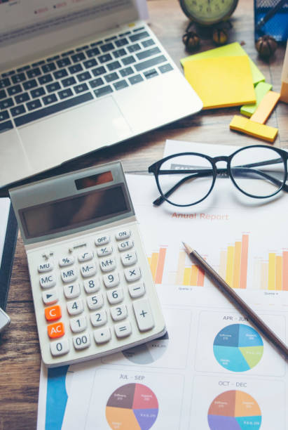 istock Business computer office wooden desk with annual report, summary report, document, paper, calculator, cup of coffee, and working space. Business executive office desk concept-vertical image. 2171365314