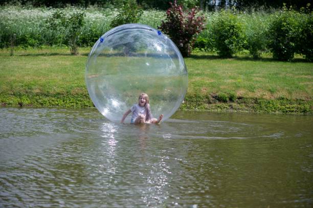 istock Young girl playing in inflatable ball on pond 2171366945