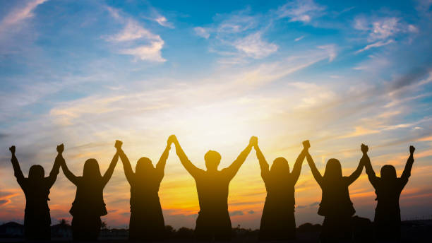 istock Group of People Standing with Raised Hands in Unity and Joy under Beautiful Sunset Sky, Celebrating Together 2171378545