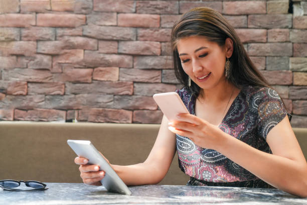 istock Smiling asian woman drinking coffee and using tablet in the cafe 2171380568