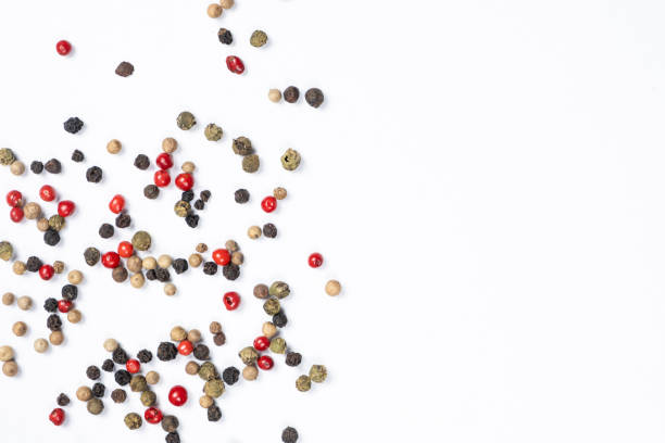 Red, green, white and black peppercorns on a white background, copy space for text.