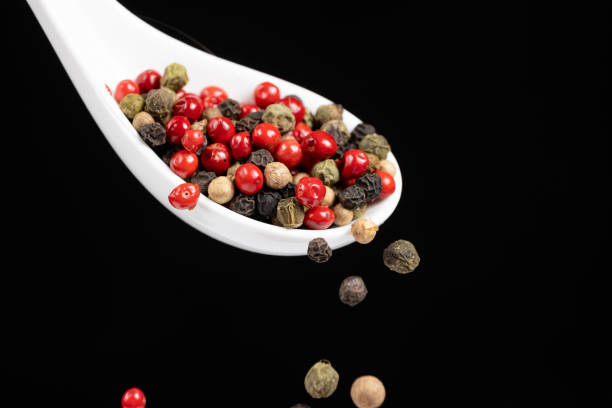 Different types of peppercorns pouring. Red, green, white and black pepper