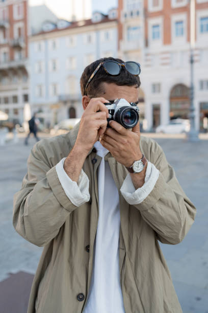 istock Young, upscale man takes photos in town square 2171390866