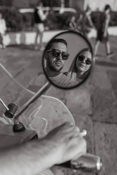 Reflection in mirror of young, upscale couple on moped , Trieste