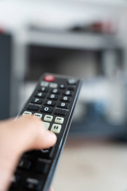 istock Hand Holding TV Remote Pointing at Blurred TV in Background 2171422752