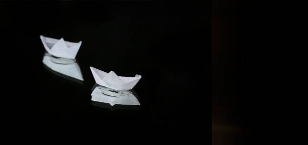artistic still life with white tiny origami boats on a dark background
