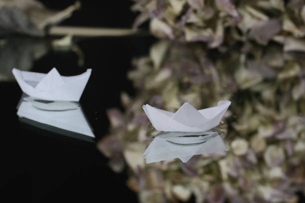 artistic still life with white tiny origami boats on a dark background