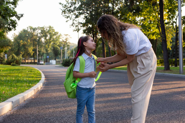istock Mother helping daughter with backpack on sunny morning walk to school 2171440909
