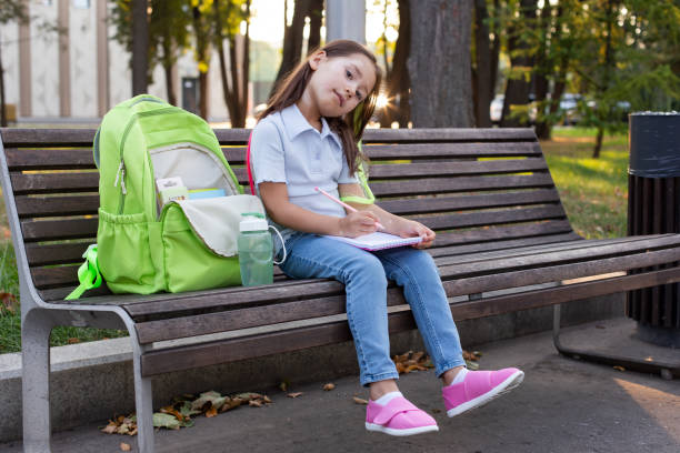 istock Young girl with backpack sketching on park bench on a sunny day 2171443663