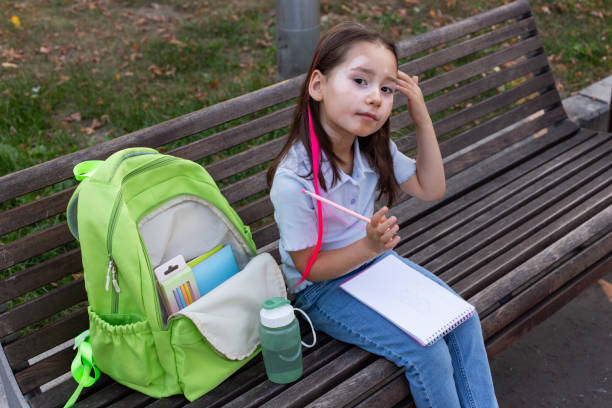 istock Child drawing outdoors: young girl with backpack and sketchpad on park bench 2171443854