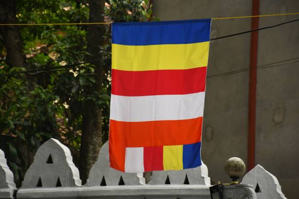 istock Buddhist flag hanging outdoors with a background of trees and a concrete wall 2171446208