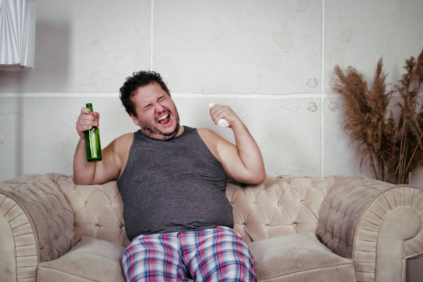 istock A fat lazy man is watching a match at home. 2171448389