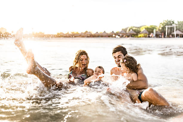 istock Young happy family having fun while splashing water in sea. 2171448629