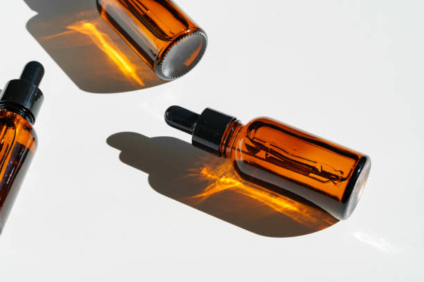 istock Arranged Amber Glass Bottles With Droppers on White Surface Accentuated by Shadows in Bright Light 2171449111