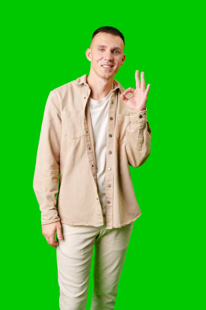 istock Man Smiling and Making Okay Gesture Against Bright Green Background 2171449472
