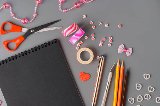 istock Crafting supplies arranged on a gray surface with a blank notebook, scissors, washi tape, and colorful embellishments 2171451265