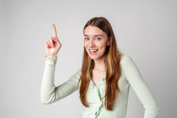 Young Woman Pointing Upwards With a Smile close up