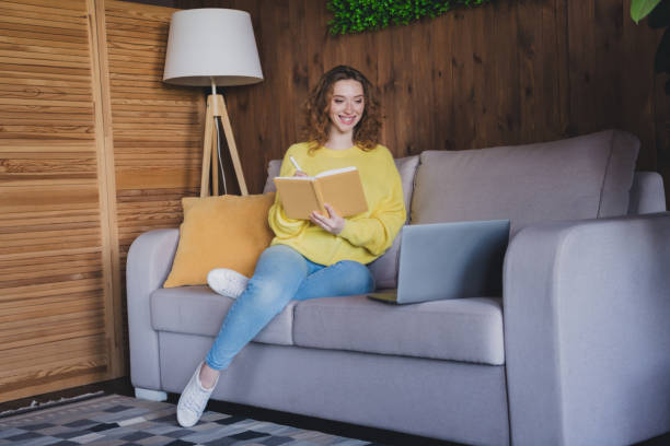 istock Full size photo of attractive young female sit couch elearning notebook dressed yellow sweater cozy day light home interior living room 2171466066