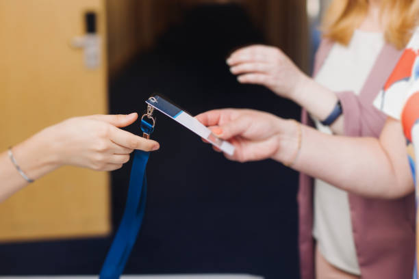 Process of checking in on conference congress forum event, registration desk table, visitors and attendees receiving lanyard with name badge and entry wristband bracelet and register electronic ticket