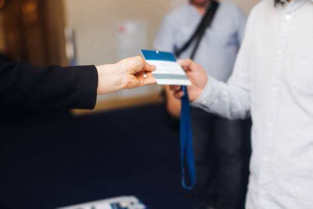 istock Process of checking in on conference congress forum event, registration desk table, visitors and attendees receiving lanyard with name badge and entry wristband bracelet and register electronic ticket 2171467520