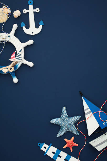 istock Nautical elements like anchors, starfish, lighthouse, wheel, and sailboat on a deep blue background. Flat lay, top view, vertical 2171467967