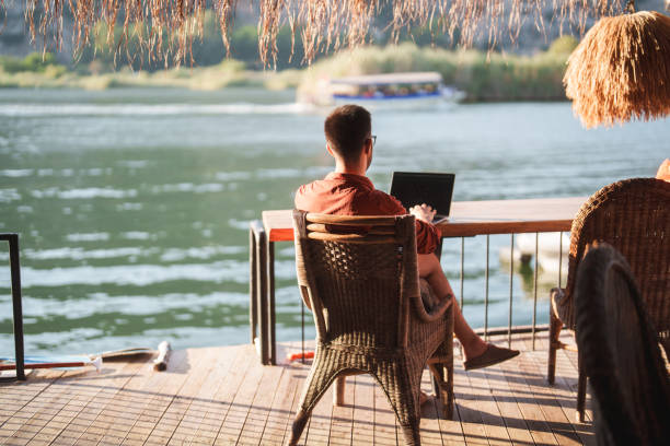 istock Man is using his laptop with a river view during his summer vacation. 2171469123